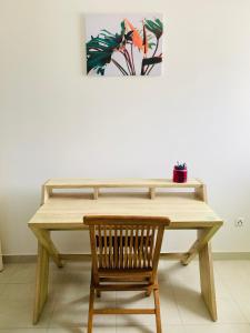 a wooden table with a chair and a picture on the wall at L’Appart Watalibi in Sainte-Luce