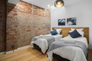 2 Betten in einem Zimmer mit Ziegelwand in der Unterkunft Saddlers House - The Retreat - Private Balcony in Hobart