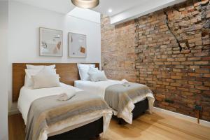 two beds in a room with a brick wall at Saddlers House - Vintage Suite - Cafe Lifestyle in Hobart