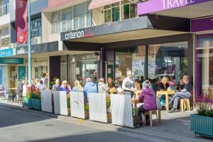 eine Gruppe von Personen, die außerhalb eines Gebäudes an Tischen sitzen in der Unterkunft Saddlers House - City View - Cafe Lifestyle in Hobart