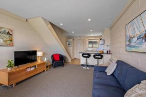 un salon avec un canapé bleu et une télévision dans l'établissement SOHO apartment with river views stroll cafes, à Hobart