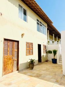Casa blanca con puertas de madera y patio en Villa do Nino en Canoa Quebrada