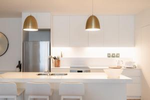eine Küche mit weißen Schränken und einem Kühlschrank aus Edelstahl in der Unterkunft The Rox - Luxe Hobart City Apartment in Hobart