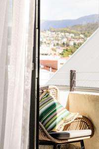 wiklinowy fotel siedzący na balkonie z oknem w obiekcie The Rox - Luxe Hobart City Apartment w mieście Hobart