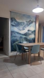 a table and chairs in a room with a painting at La maison des créatifs in Montdardier