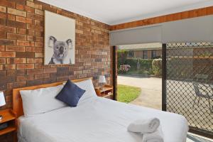 a bedroom with a bed and a brick wall at Kellraine Holiday Units in St Helens