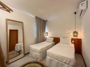 ein kleines Zimmer mit zwei Betten und einem Spiegel in der Unterkunft Villas Manatee Apartamento G103 Nobile Stays in Tatuamunha + 56 Fotos
