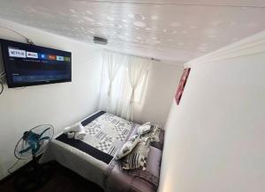 Habitación pequeña con cama y TV en la pared. en Habitaciones en casa de alojamiento sector sur de Iquique, Chile, en Iquique