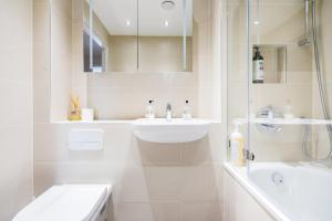een witte badkamer met een wastafel en een douche bij The Wentworth Apartment - Sleeps 4 in Londen