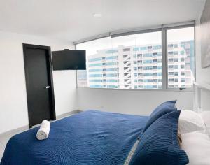 1 dormitorio con cama azul y ventana grande en Lujoso depa con vista a todo Guayaquil!, en Guayaquil