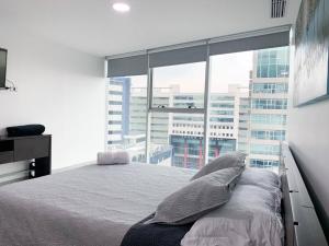 a bedroom with a bed and a large window at Lujoso depa con vista a todo Guayaquil! in Guayaquil