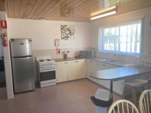 a kitchen with a stainless steel refrigerator and a table at Kellraine Holiday Units in St Helens