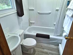 La petite salle de bains est pourvue de toilettes et d'une baignoire. dans l'établissement Sea Breeze Motel, à Ingonish