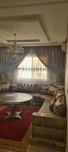 a living room with a table and a large window at Résidence nahda in Agadir