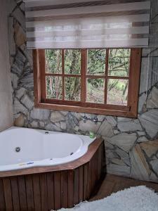 uma banheira na casa de banho com uma janela em Chalé dois irmãos em Visconde de Mauá
