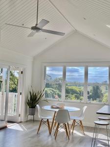 een witte kamer met een tafel, stoelen en ramen bij Sunnycrest Hinterland Heaven in Bangalow