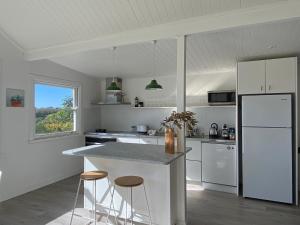 een keuken met witte apparaten en een aanrecht met krukken bij Sunnycrest Hinterland Heaven in Bangalow