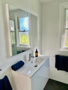 een witte badkamer met een wastafel en een spiegel bij Sunnycrest Hinterland Heaven in Bangalow