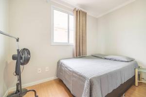 a white bedroom with a bed and a window at QUARTO privativo para 1 pessoa em Home Club in Balneário Camboriú