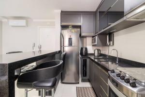 a kitchen with a stainless steel refrigerator and black counter tops at QUARTO privativo para 1 pessoa em Home Club in Balneário Camboriú