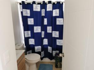 a bathroom with a toilet and a blue shower curtain at Lomas 5 in Papudo