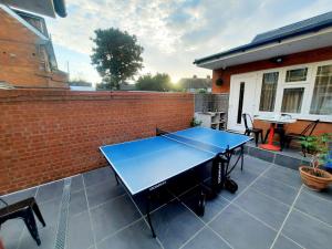 a ping pong table on a patio with a brick wall at Min Su Rooms in Stanwell