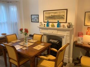een eetkamer met een tafel en een open haard bij Queens Cottage Salisbury in Salisbury