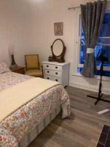 een slaapkamer met een bed, een spiegel en een raam bij Queens Cottage Salisbury in Salisbury