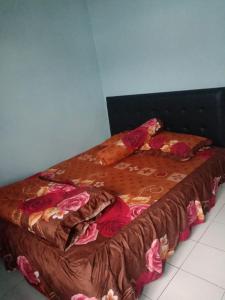 ein Bett mit brauner Bettdecke und Kissen darauf in der Unterkunft Dedwa Homestay syariah in Batu + 3 Fotos