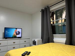 a bedroom with a bed and a tv and a window at Serene Full Bed with 50 Inch Smart TV, Netflix, AirPlay, Mini-Fridge, and 500 Mbps WiFi near FIU, Dolphin Mall, Airport in Miami