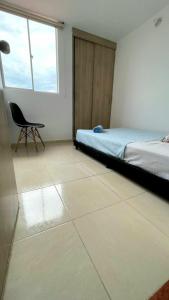a bedroom with a bed and a chair and a window at ST Apto lindo y comodo in Neiva