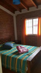 1 dormitorio con 1 cama con una manta colorida y una ventana en Cabaña en El Trapiche Jotita Jota en Trapiche