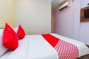 a bedroom with a bed with red pillows at OYO Hotel Stayland Near Juhu Beach in Mumbai
