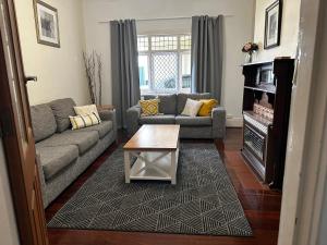 uma sala de estar com um sofá e uma mesa em Glenelg House em Adelaide