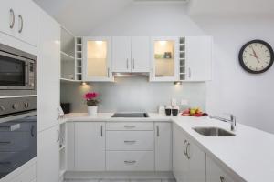 a kitchen with white cabinets and a clock on the wall at Charm on Carrington in Adelaide