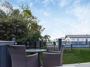 a patio with chairs and a table with a view of a house at Copse View in Kelsale