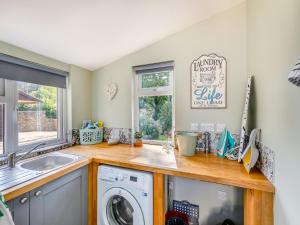 a kitchen with a sink and a washing machine at Holly Cottage in Clearwell