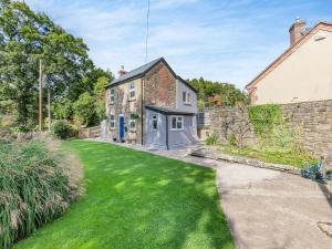 Holly Cottage في Clearwell: اطلالة خارجية على منزل مع ساحة خضراء