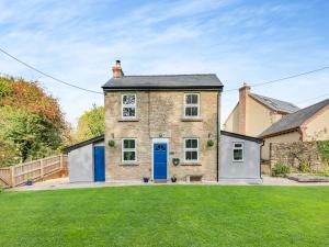 una casa de ladrillo con una puerta azul y un patio en Holly Cottage, en Clearwell