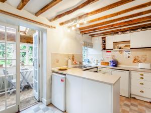 uma cozinha com armários brancos e uma grande janela em Old Orchard Cottage em Dilton