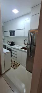 uma cozinha com armários brancos e electrodomésticos de aço inoxidável em Quarto privativo Interlagos autódromo em São Paulo