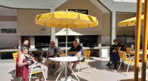a group of people sitting around a table with an umbrella at Apart Hotel La Recova in Termas de Río Hondo