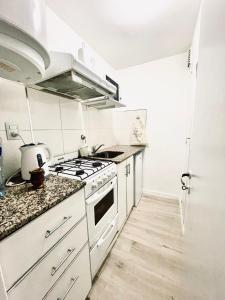 a white kitchen with a stove and a sink at Suite Centro con COCHERA in Bahía Blanca