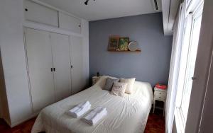 1 dormitorio con 1 cama blanca y 2 toallas en V&A en Buenos Aires