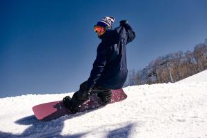 a man riding a snowboard down a snow covered slope at Hotel Silk Inn Madarao in Iiyama
