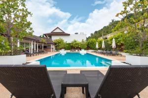 una piscina in un hotel con sedie e ombrelloni di Beachside Apt. Short Walk to Nai Harn Beach - 2BR a Nai Harn Beach