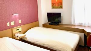 越谷市にあるビジネスホテル雷鳥のベッド2台、薄型テレビが備わるホテルルームです。