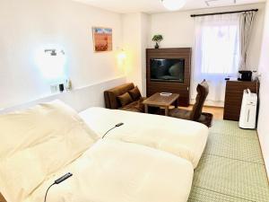 a living room with a couch and a tv at Business Hotel Raicho in Koshigaya
