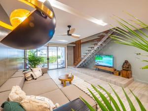 a living room with a staircase and a television at Stylish Townhouse near Fisherman in Amphoe Koksamui