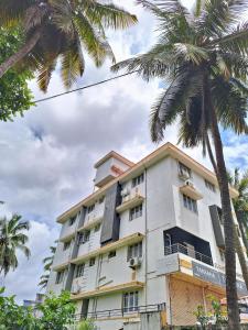 a white building with palm trees in front of it at Suvarna Grande Homes in Mangalore